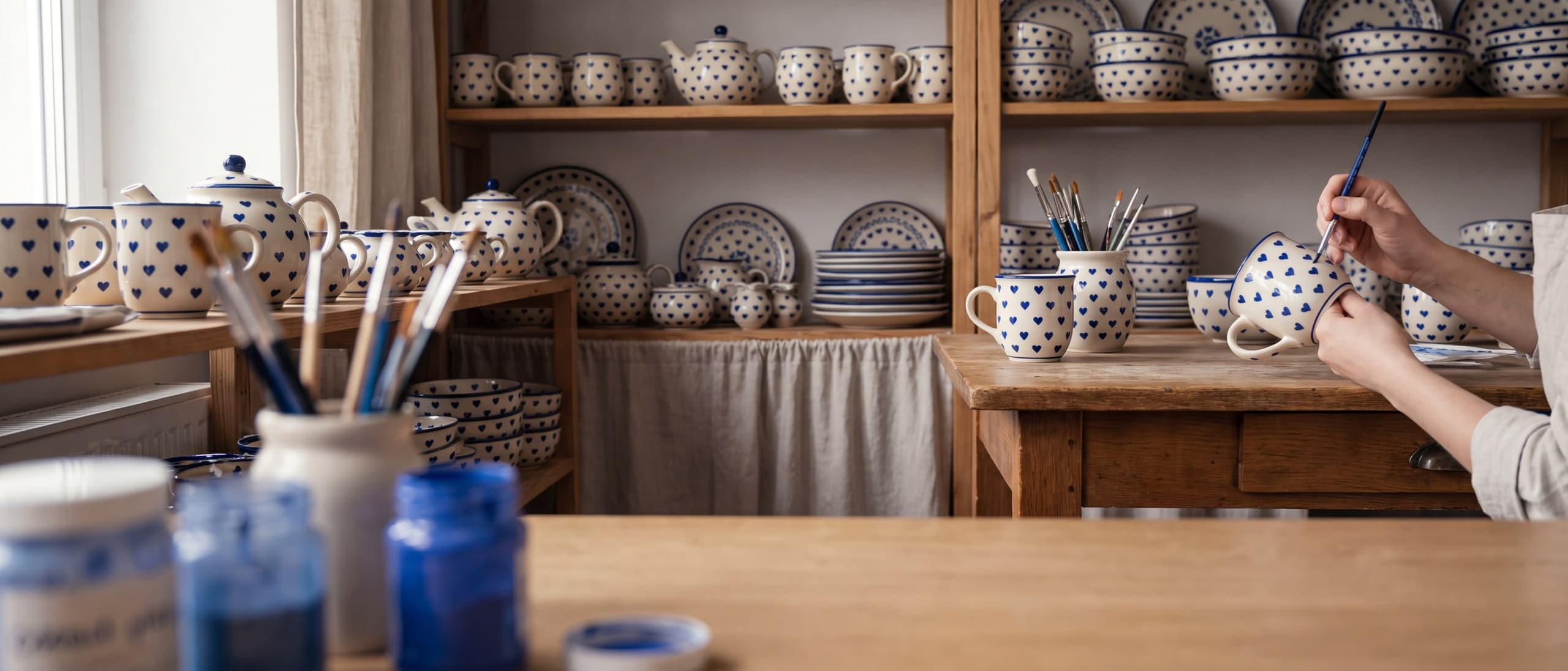 Pracownia Lady Blue w Bolesławcu — malowanie kubka przy regale z gotową ceramiką